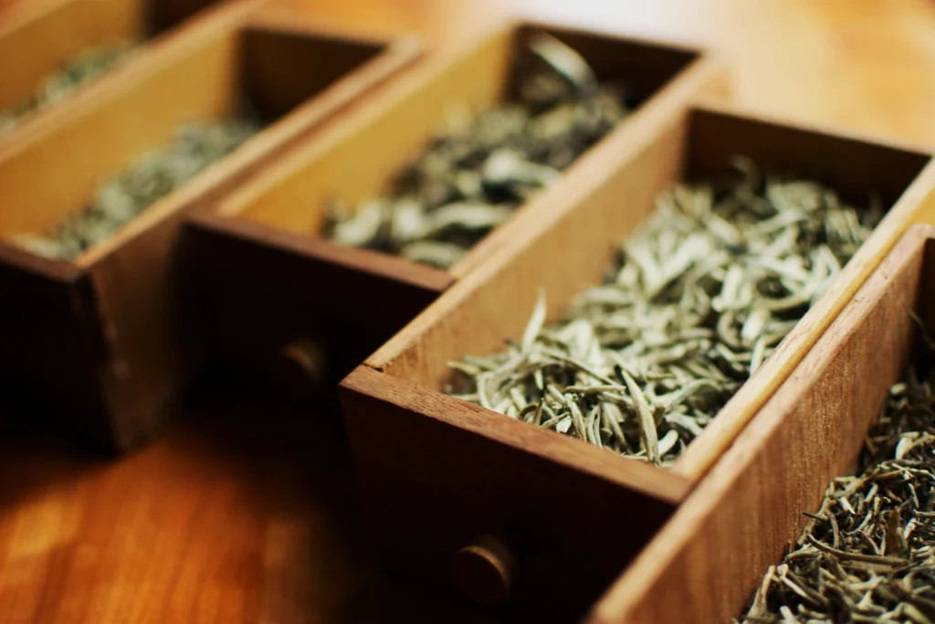 Wooden boxes filled with dried tea leaves on a wooden surface. The image conveys a rustic and natural tone, highlighting textures and earthy colors.