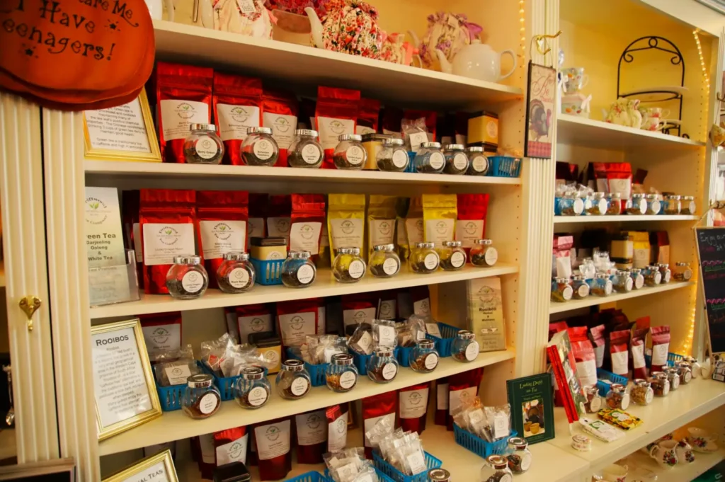 A cozy shop display featuring shelves with colorful tea bags, small jars, and various accessories. Warm lighting creates an inviting, charming atmosphere.