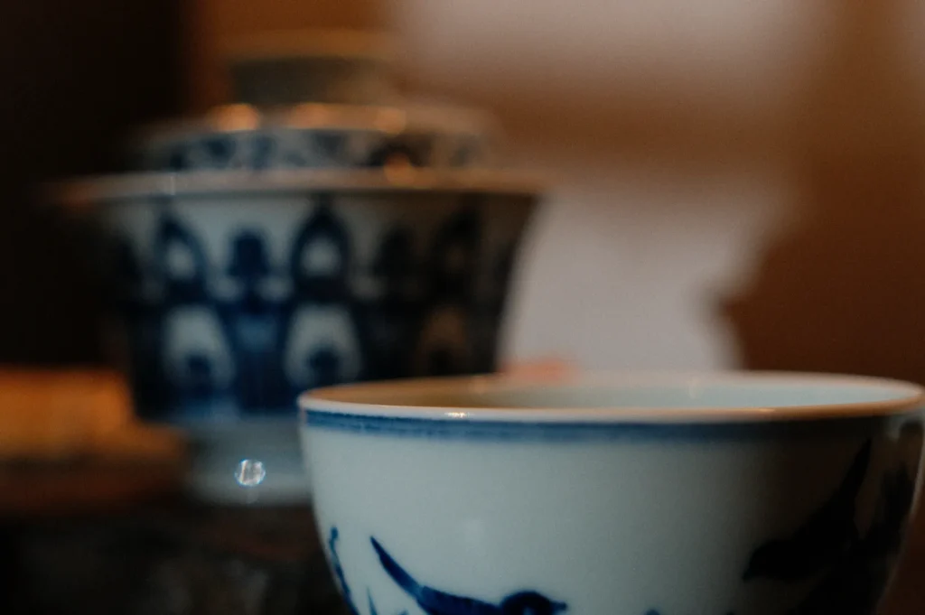Close-up of a blue and white ceramic bowl with intricate designs, sitting in soft focus against a blurred background, conveying a serene, vintage feel.
