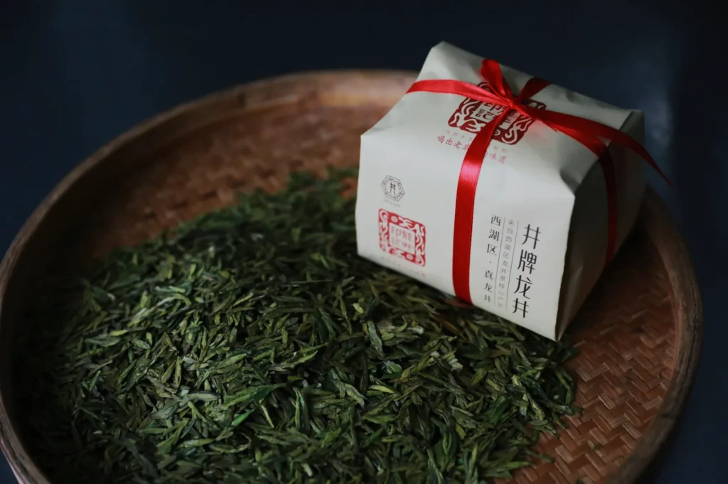 A basket of dried green tea leaves with a beige packaging tied with a red ribbon. The setting exudes a traditional, artisanal, and authentic feel.