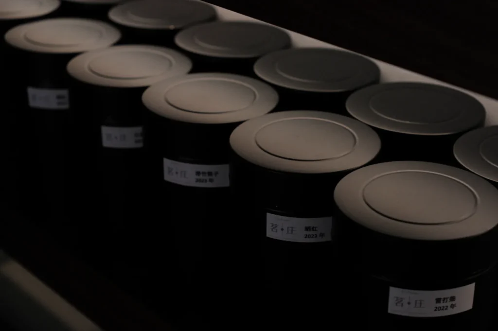 A row of black cylindrical containers with labeled tops, arranged neatly on a shelf.