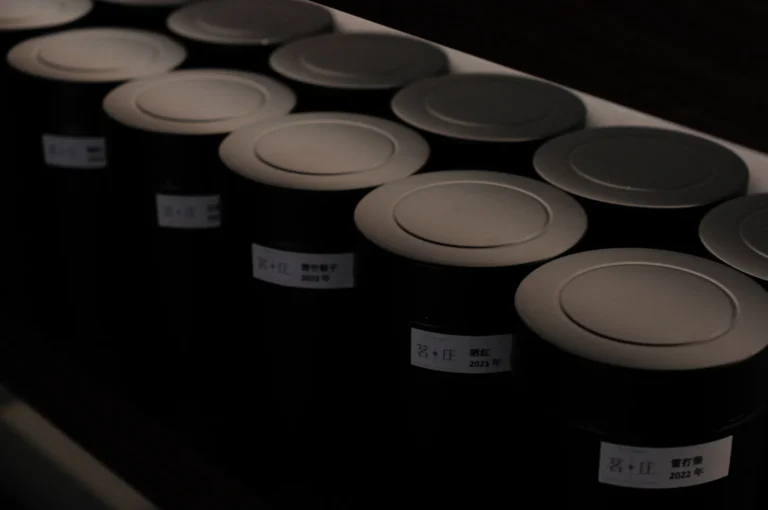 A row of black cylindrical containers with labeled tops, arranged neatly on a shelf.