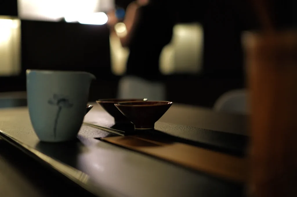 A close-up of a table setting with a light blue cup and two red small tea cup, against a softly blurred background.