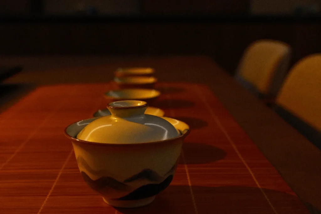 A row of traditional Japanese tea bowls on a wooden table, illuminated by soft, warm light.