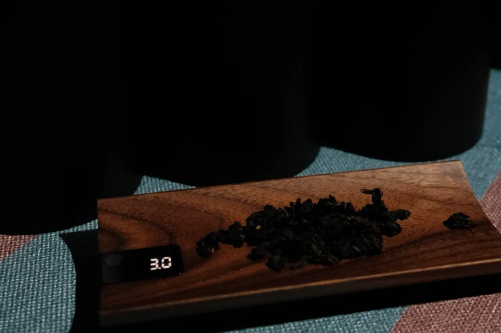 A wooden tray displaying a small amount of black tea leaves, with a digital scale showing a weight of 3.0.
