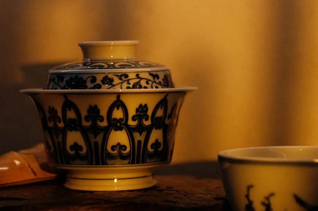 A decorative ceramic bowl with blue patterns, illuminated by warm, golden light, placed on a wooden surface.