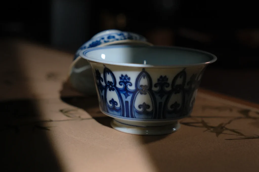 A delicate ceramic tea cup with blue and white floral patterns, partially in shadow.