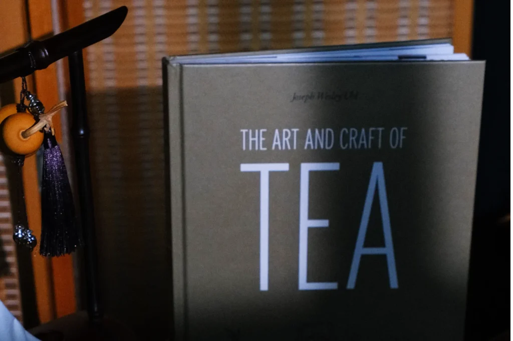 A book titled "The Art and Craft of Tea" is partially visible, with a tassel and a knife in the foreground.