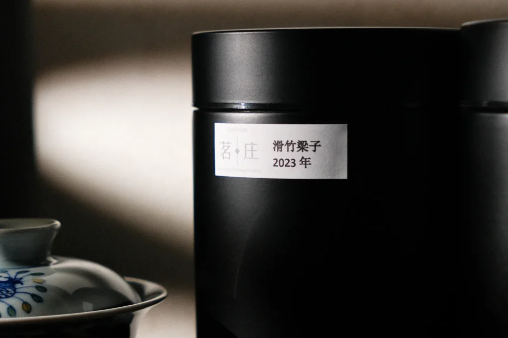 A close-up of black cylindrical containers with a label that reads "清竹英子 2023年," next to a decorative dish.