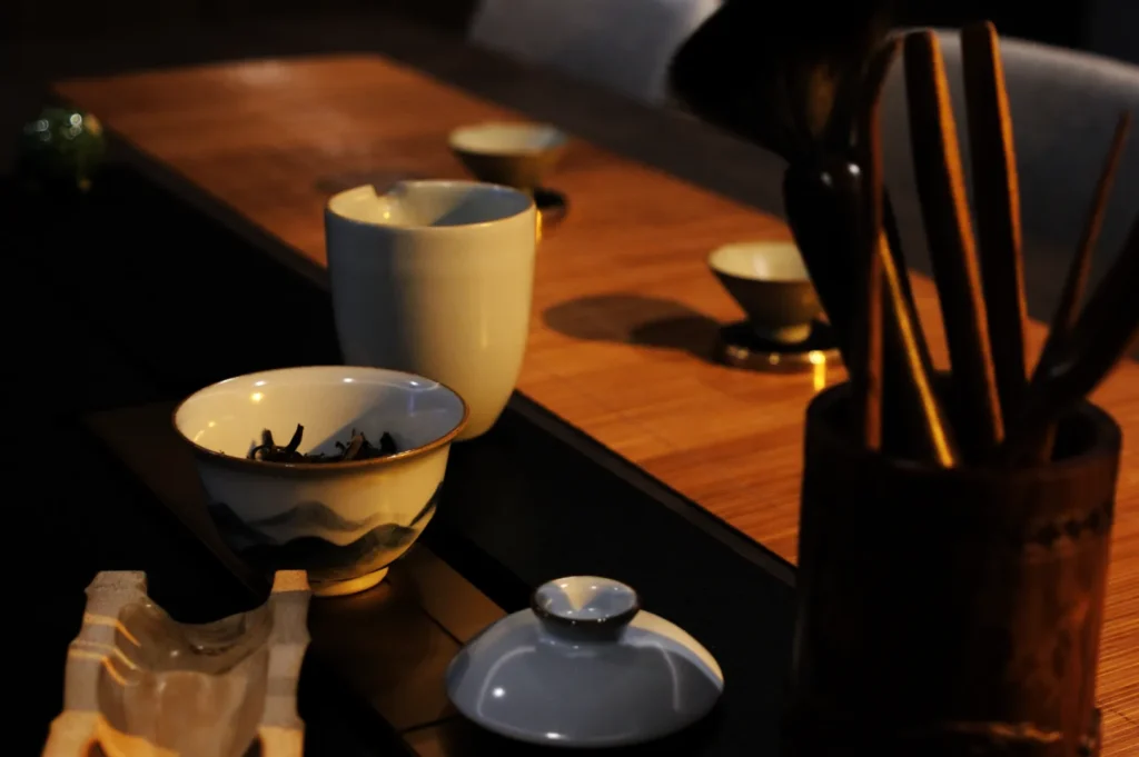 A serene table setting featuring various ceramic bowls and utensils in dim lighting, with a focus on a blue and white bowl.