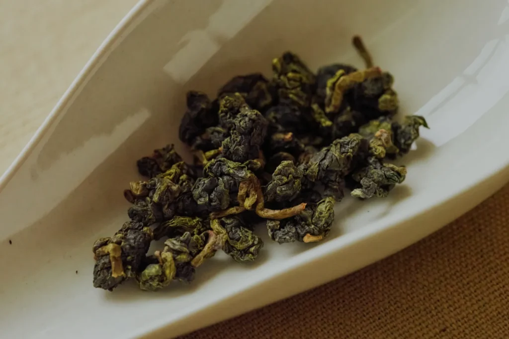 Dried oolong tea leaves on a small white dish.