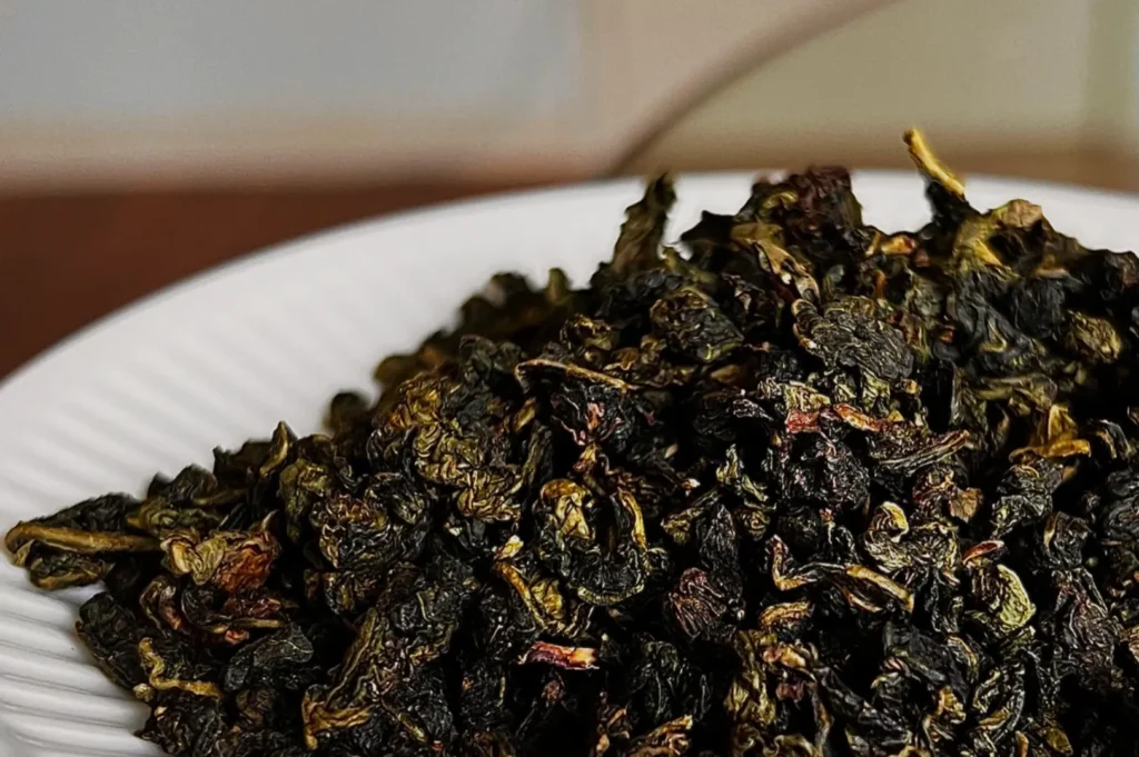 A close-up of dried oolong tea leaves on a white plate.