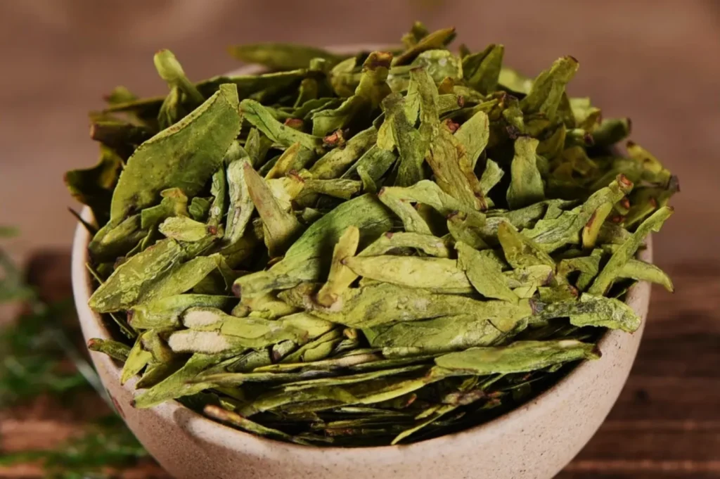 A bowl filled with dried green herbs or leaves.