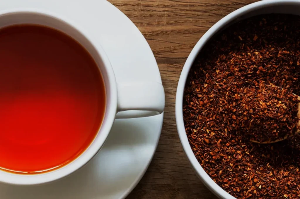 A cup of reddish-brown tea next to a bowl of reddish spice or seasoning.