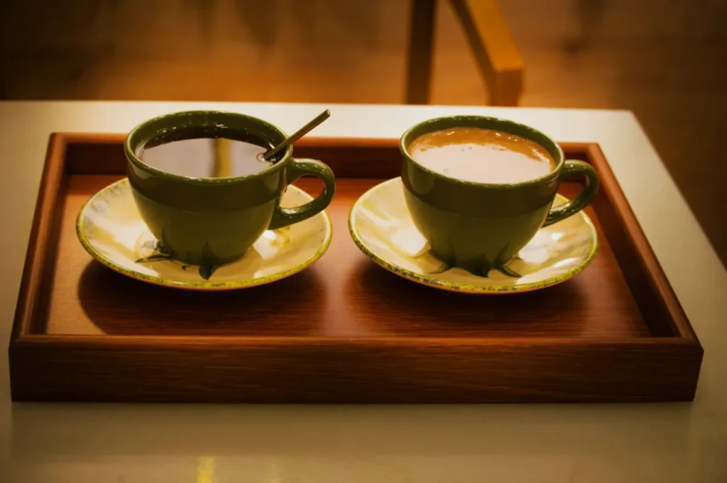 Two cups of coffee on saucers placed on a wooden tray.