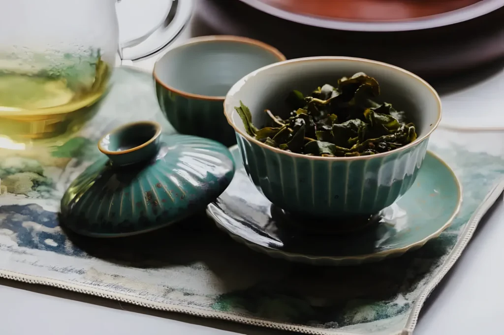 A tea set with a bowl of dried tea leaves, a small cup, and a teapot, resting on a decorative mat.