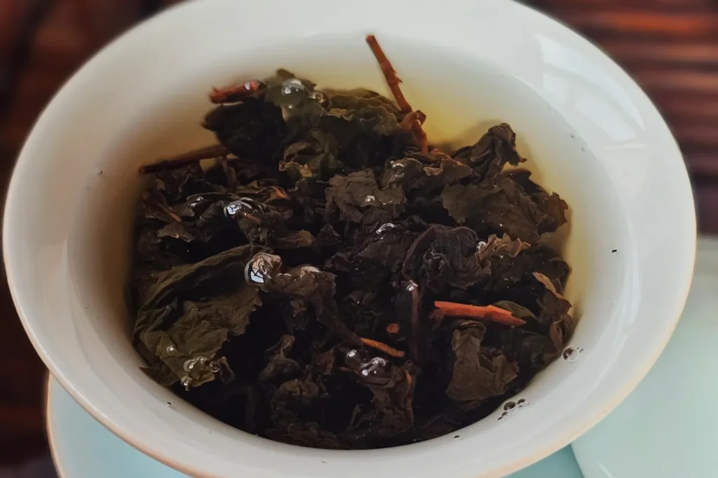 A bowl of dark, wet tea leaves steeped in water.
