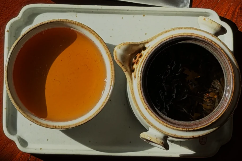 A tray with a cup of brewed tea next to a pot containing loose tea leaves.