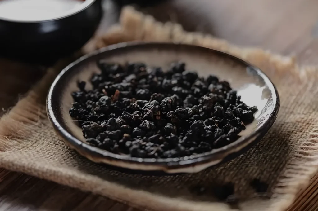 A plate of dried black tea leaves on a textured surface.