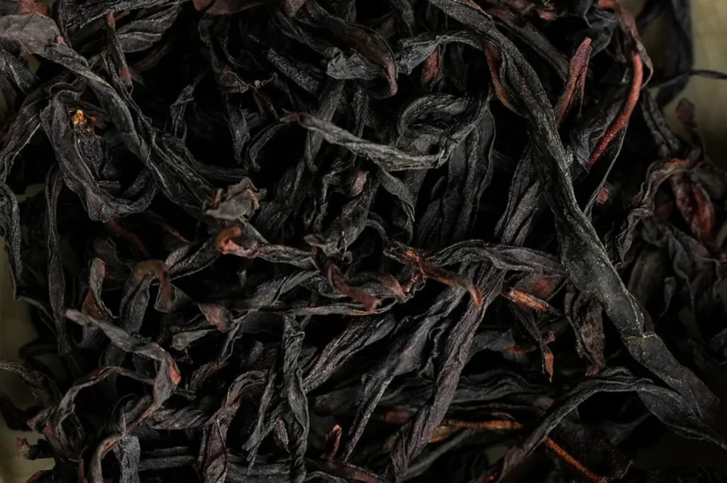 Dried black tea leaves in a white bowl.