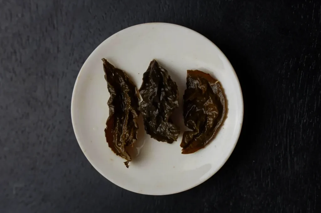 A small white plate with three pieces of dried tie guan yin on a black surface.