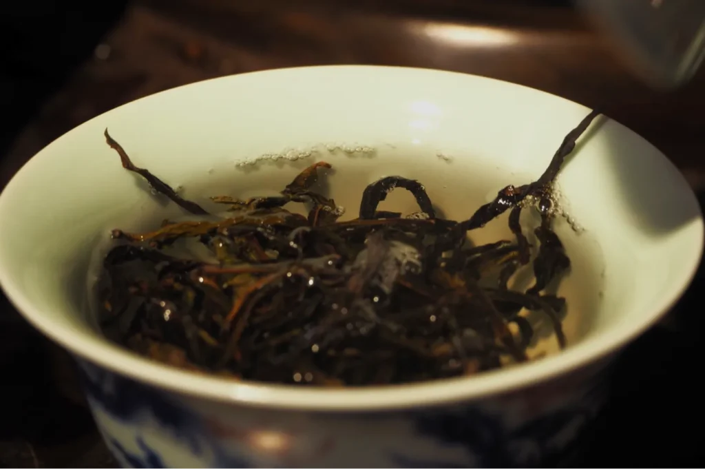 A ceramic bowl filled with dark, tangled seaweed in broth, its glossy strands rising above the surface; warm lighting gives the dish a rustic, earthy feel.